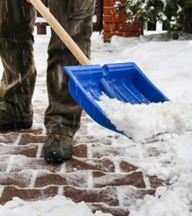 Adult shoveling snow off paved sidewalk