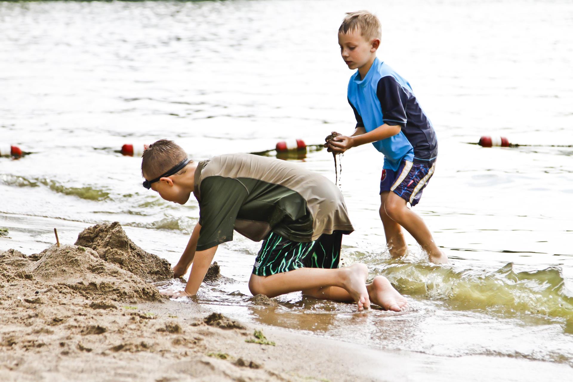 Two boys playing in the sand by the beach