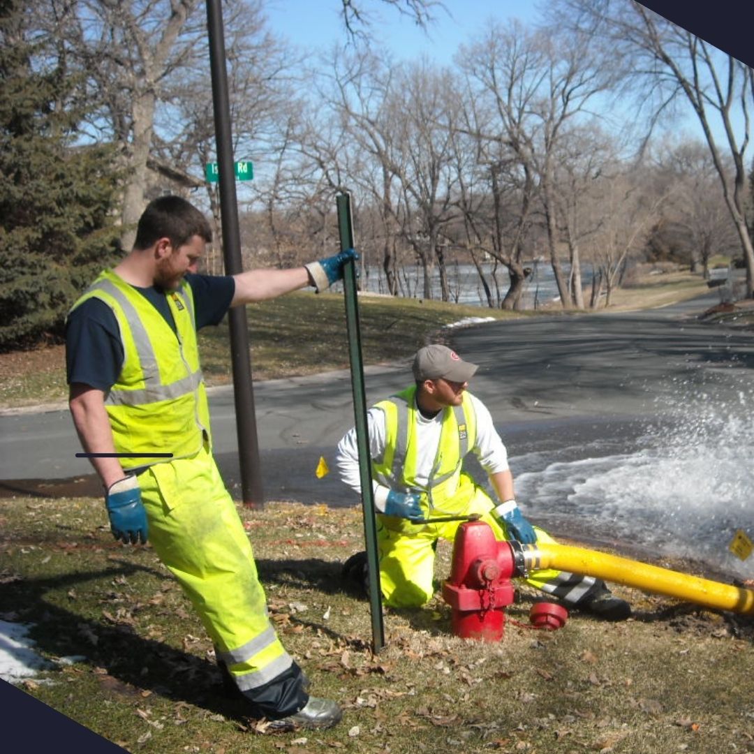 Two Public Works employees work to flush a fire hydrant