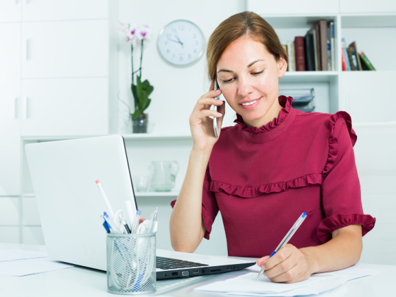 Woman on Phone While Writing in Notepad