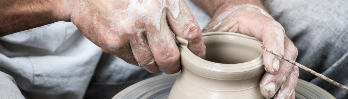 Hands creating clay bowl on pottery wheel