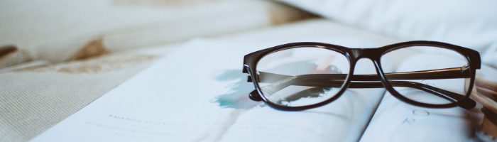 Reading glasses resting on open book