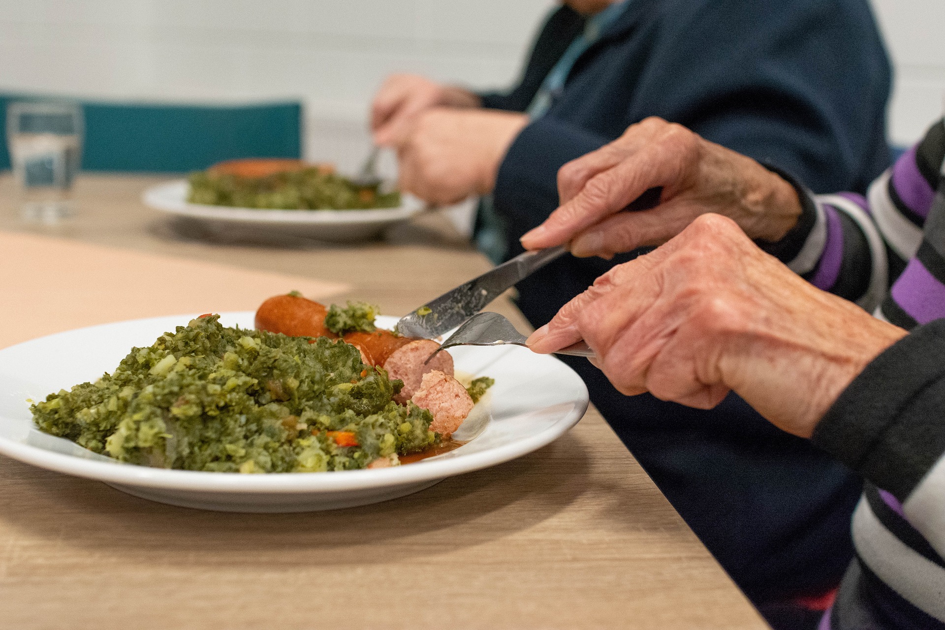 Older hands cutting food on plate